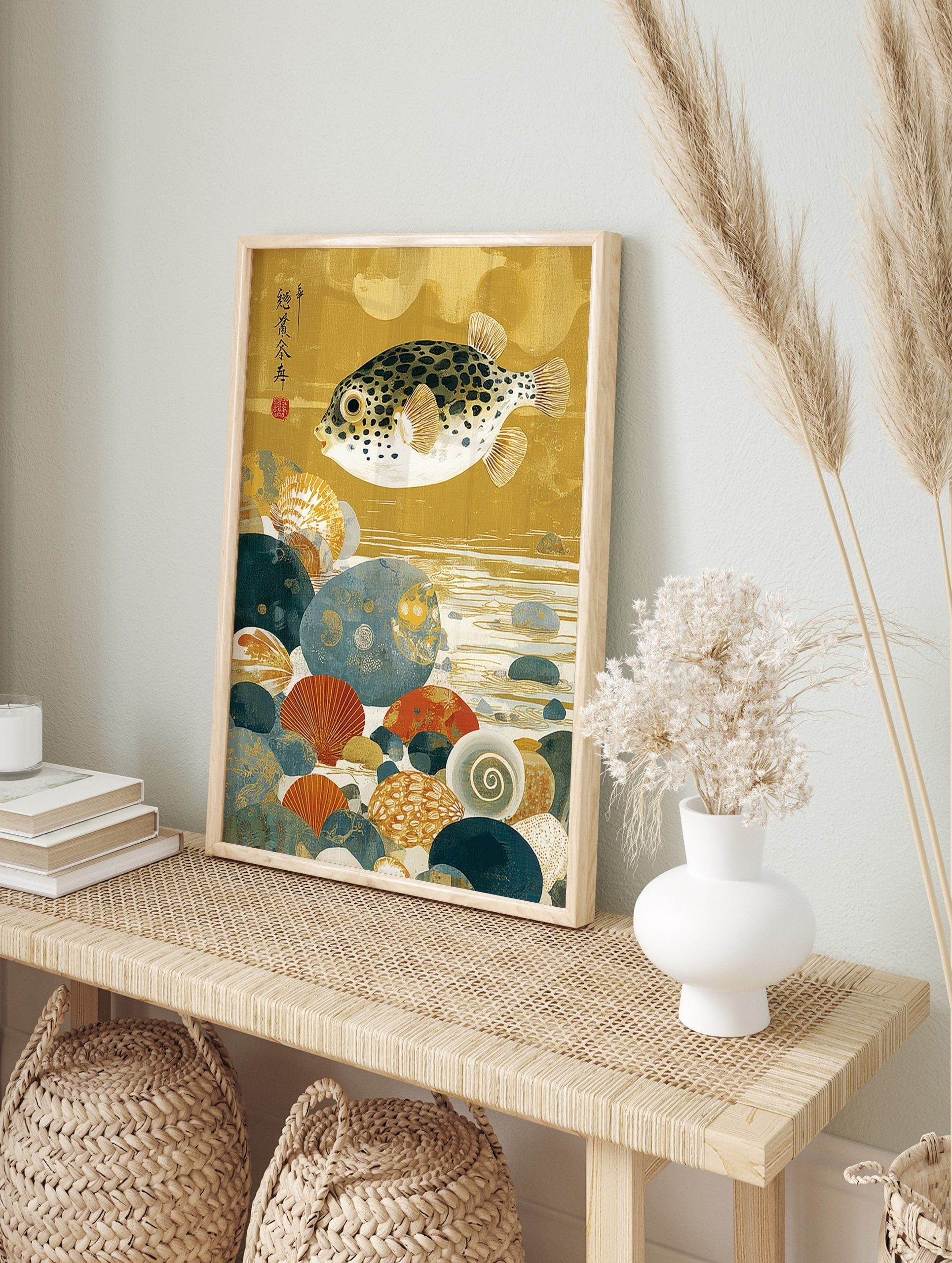 Japanese pufferfish art print with black spots, swimming over colourful seabed pebbles and, in an alternate framed mockup