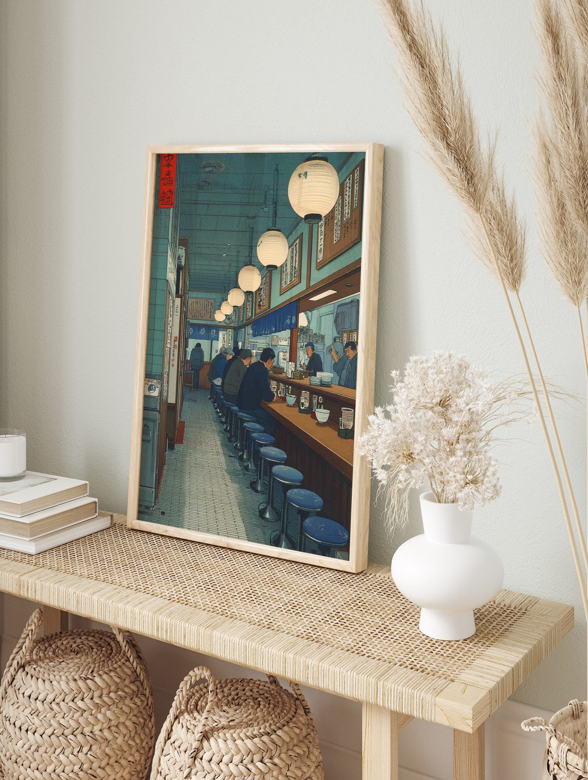 Japanese ramen bar interior art print with patrons at counter, blue stools, glowing lanterns, in an alternate framed mockup
