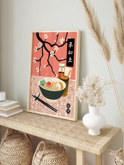 Japanese ramen poster with a bowl of noodles, egg, and greens, chopsticks, condiments, and black cherry blossom branches on a pink background. - Image 4
