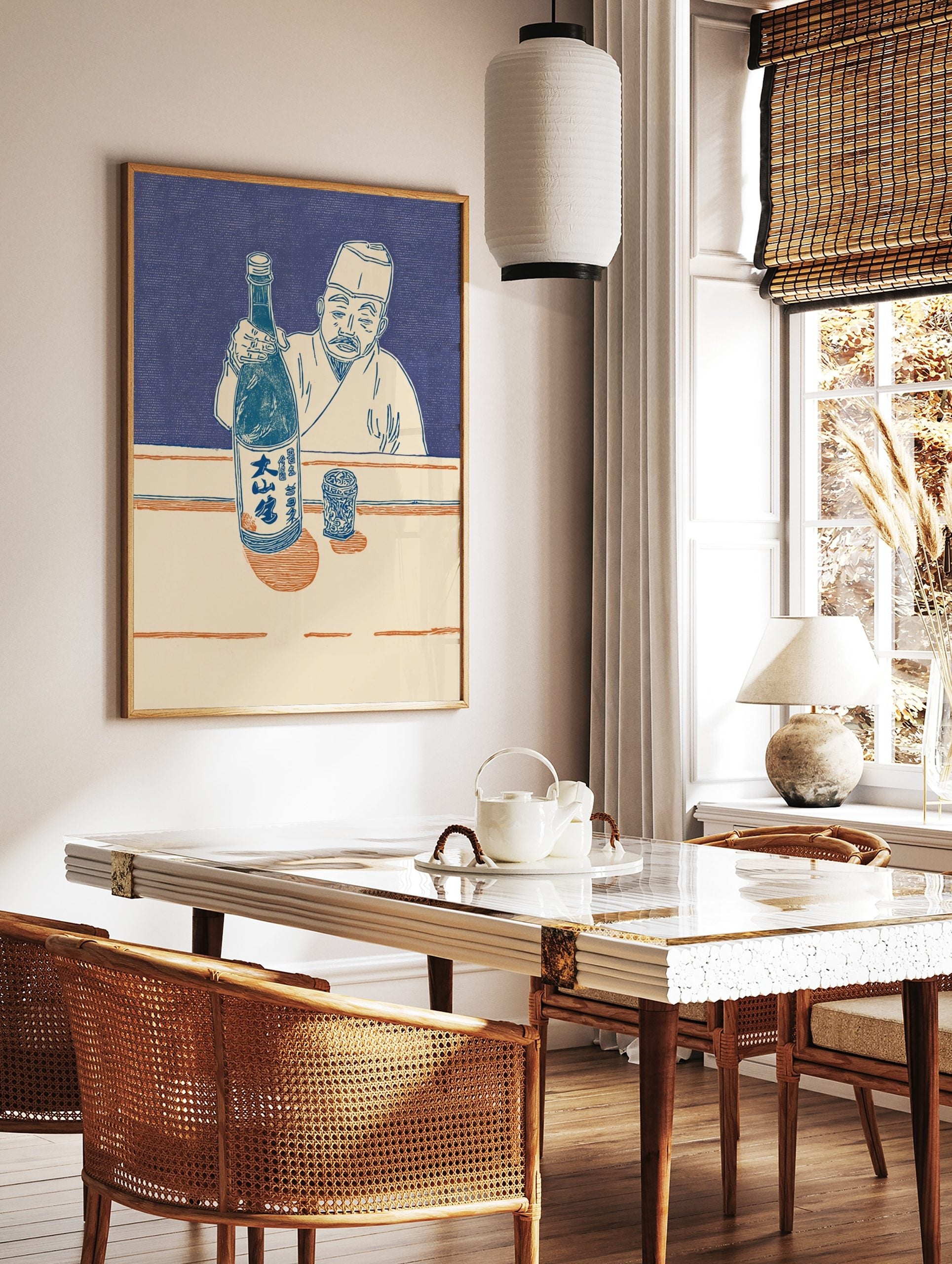 Japanese man in traditional attire holding a sake bottle and presenting it, with a patterned cup on, in a styled room mockup