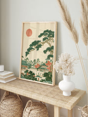 Japanese landscape art print with a pine tree, temple architecture, and a red sun on a, in an alternate framed mockup
