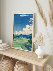 Japanese landscape wall art print with a blue train, green rice fields, mountains, and white clouds in a blue sky. - Image 3