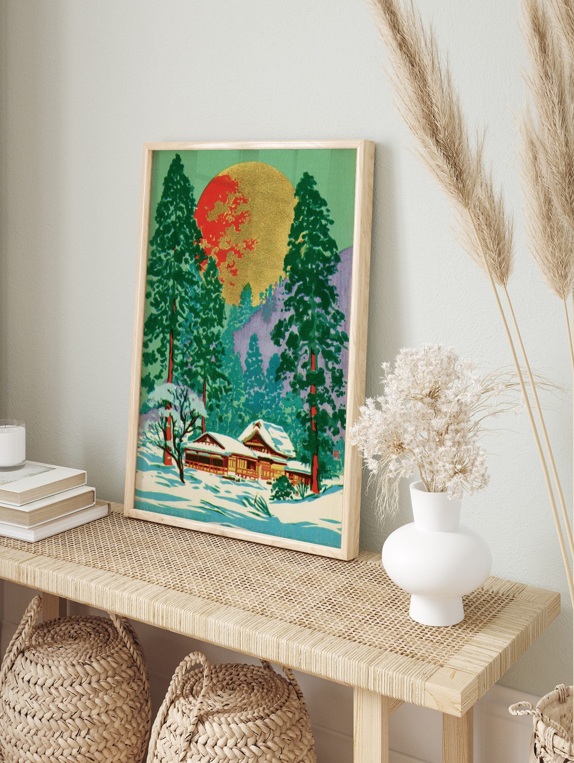 Japanese winter landscape art with snow-covered temple, green pine trees, and a large red and, in an alternate framed mockup