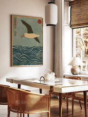 Japanese woodblock print of an albatross flying over blue waves with a red sun and kanji script, in a styled room mockup