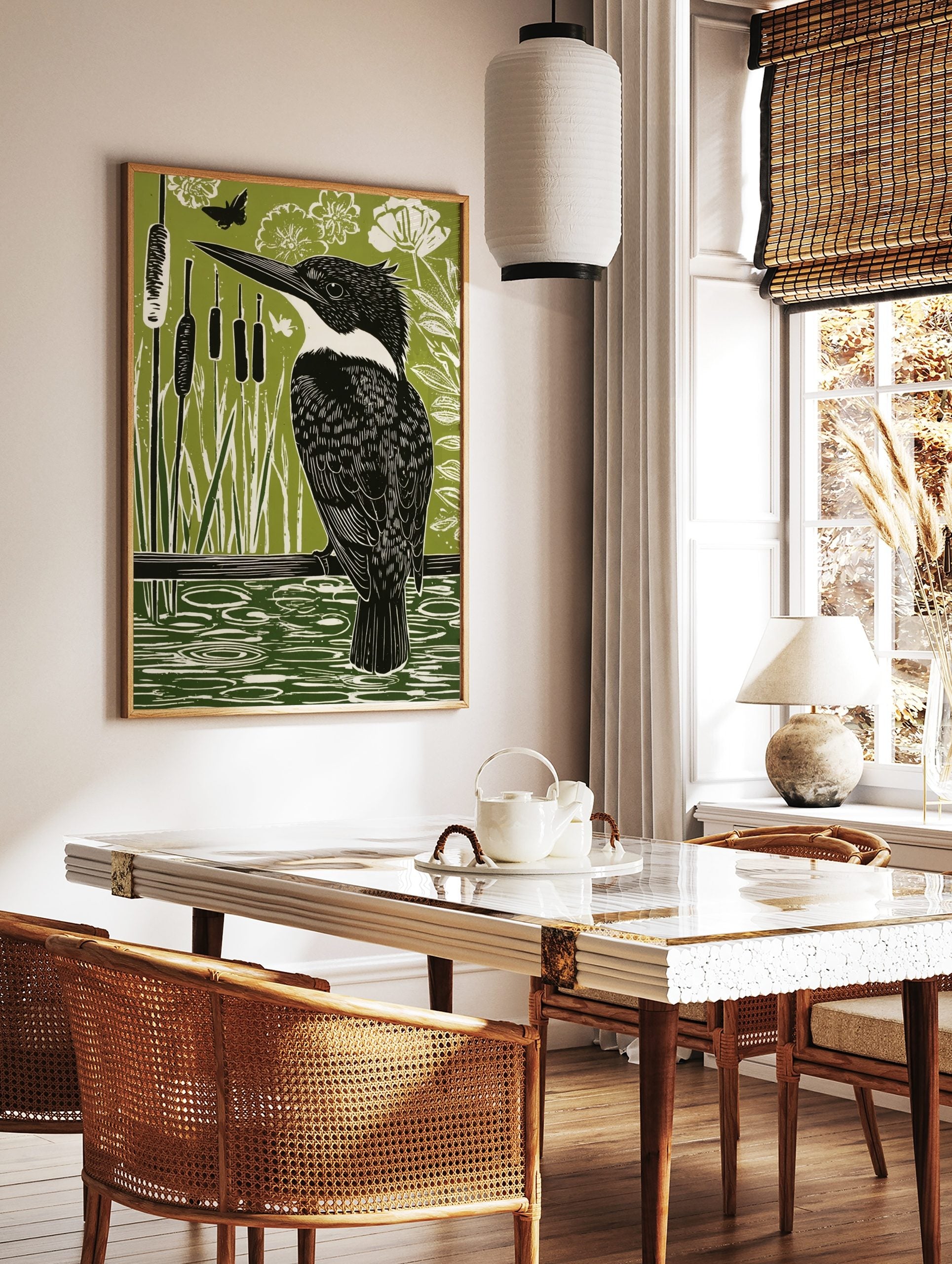 Linocut-style print of a black and white kingfisher bird on a branch over green water with reeds, in a styled room mockup