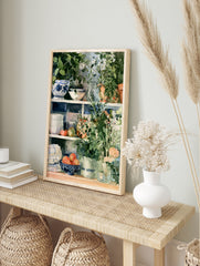 Watercolour kitchen shelf art print with blue patterned bowls, terracotta plants, and fruit, in an alternate framed mockup