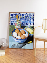 Kitchen Still Life Wall Art showing a bowl of eggs, butter, whisk, and wooden spoons against blue and white tiles. - Image 2