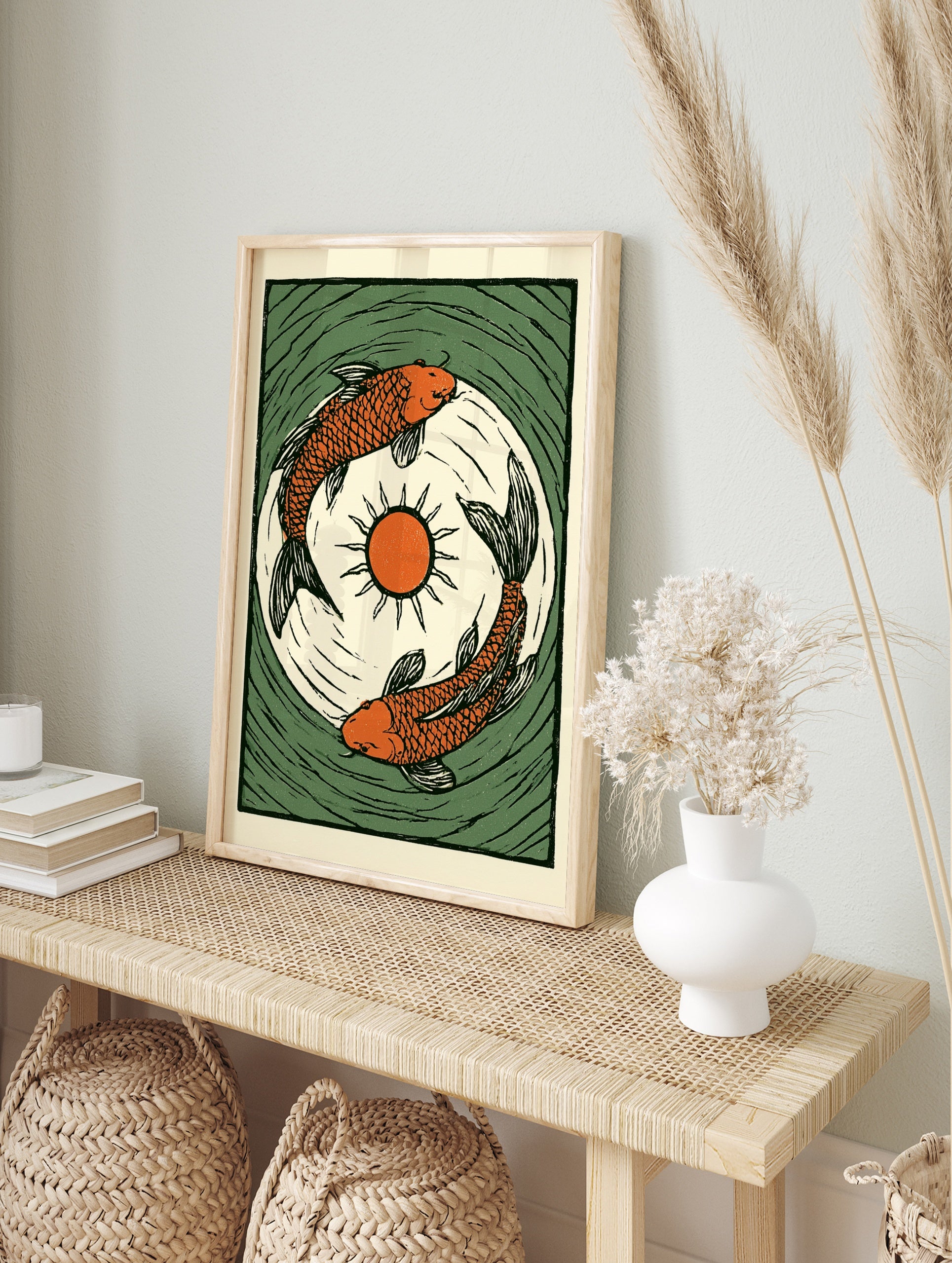 Illustrative orange koi carp fish print with central sun and green water ripples in a woodcut, in an alternate framed mockup