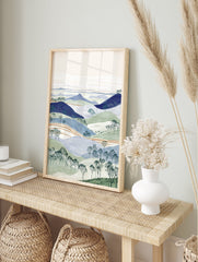 Illustrated landscape wall art with layered blue and green hills, bare trees, and a pale sky. - Image 3