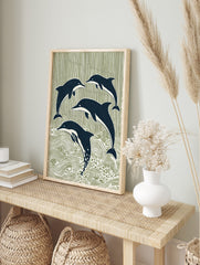 Four stylised navy blue dolphins leaping and swimming against a sage green striped and wavy, in an alternate framed mockup