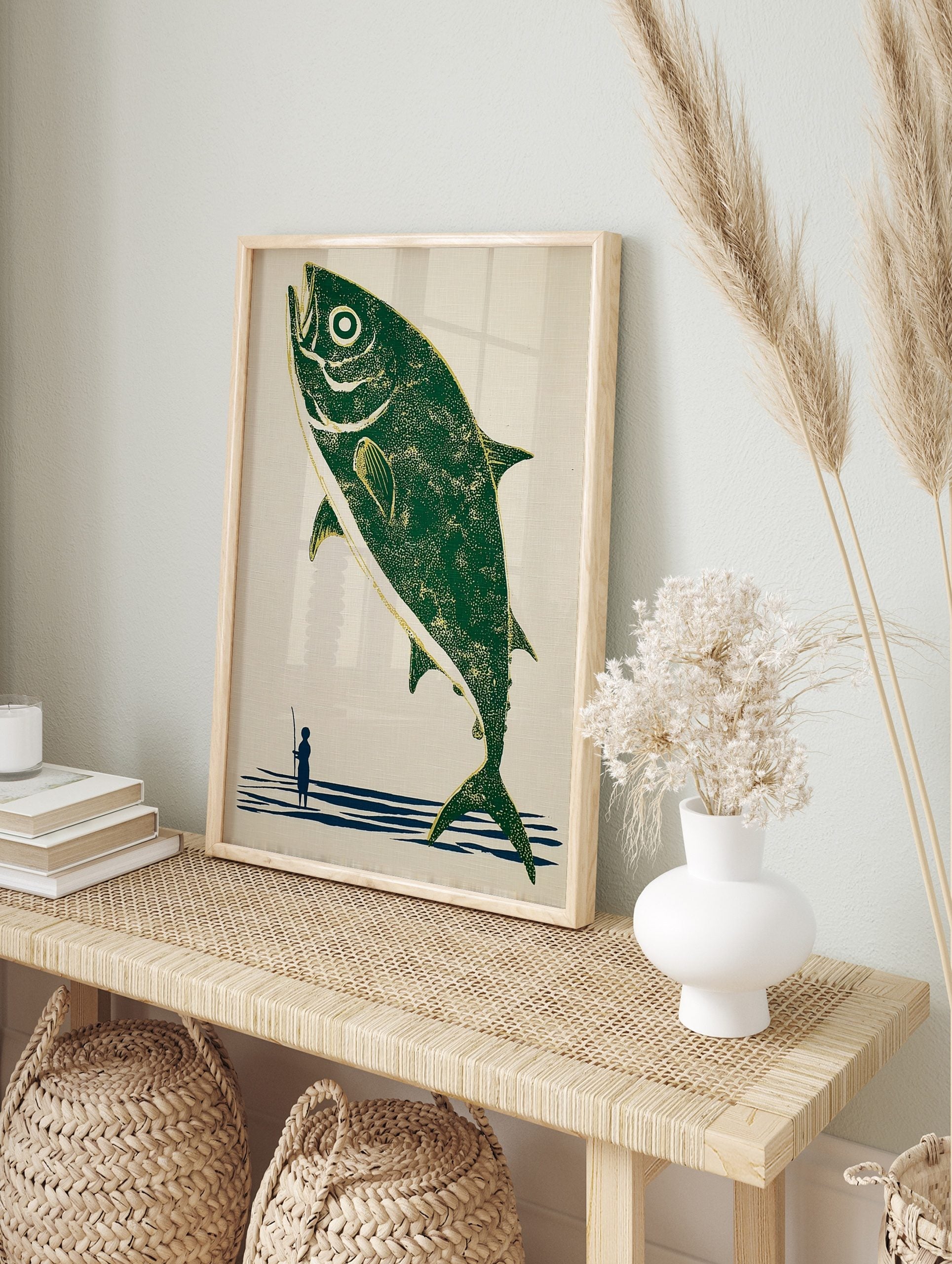 Illustrative print of a large green fish leaping from blue water, with a small fisherman, in an alternate framed mockup