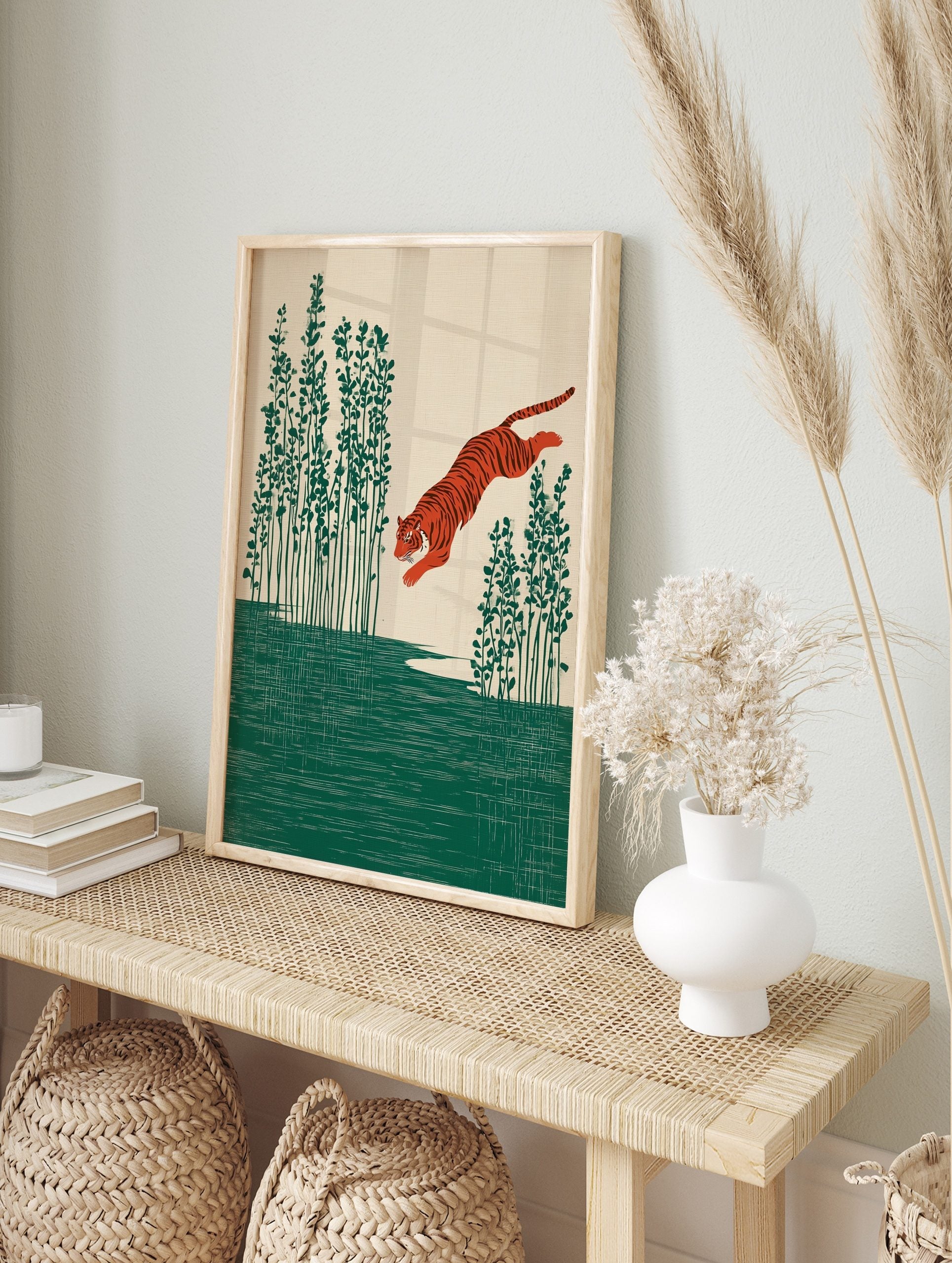 Illustrative print of an orange tiger leaping over green water with tall plants on a beige, in an alternate framed mockup