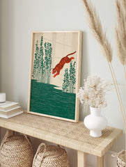 Illustrative print of an orange tiger leaping over green water with tall plants on a beige, in an alternate framed mockup