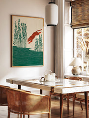 Illustrative print of an orange tiger leaping over green water with tall plants on a beige, in a styled room mockup