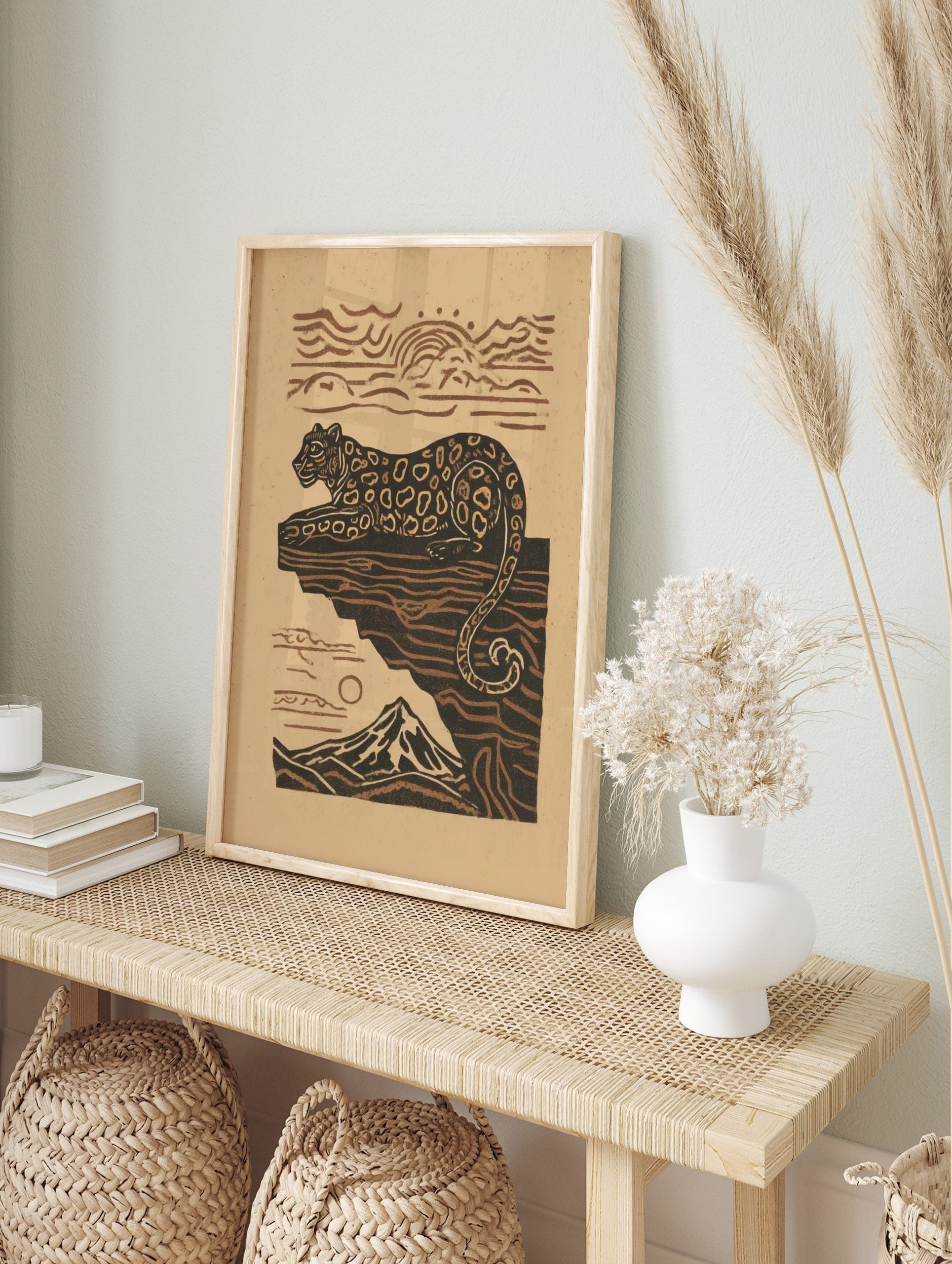 Illustrative leopard resting on a cliff with a mountain and sun in earthy brown and beige, in an alternate framed mockup