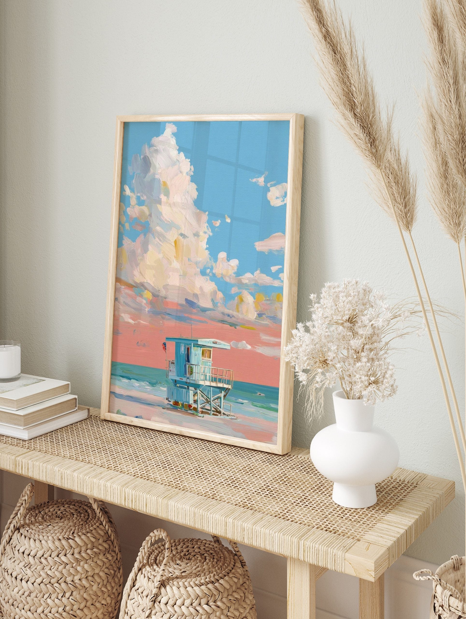 Painterly art print of a light blue lifeguard hut on a beach under a sky with large white and, in an alternate framed mockup