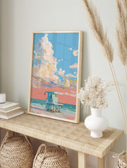 Painterly art print of a light blue lifeguard hut on a beach under a sky with large white and, in an alternate framed mockup