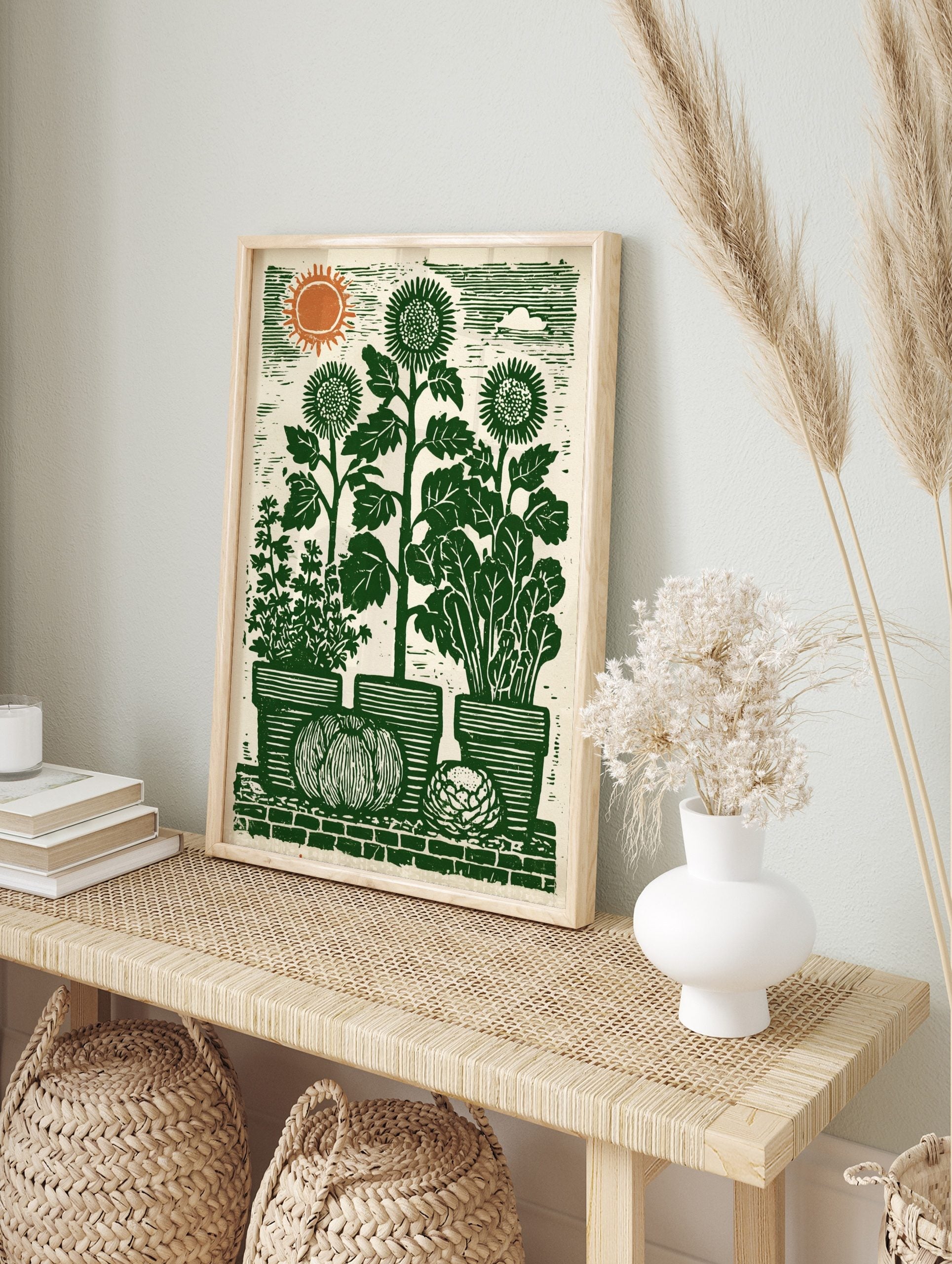 Lino-cut garden art print with sunflowers, potted herbs, pumpkin, and cabbage on a brick wall, in an alternate framed mockup