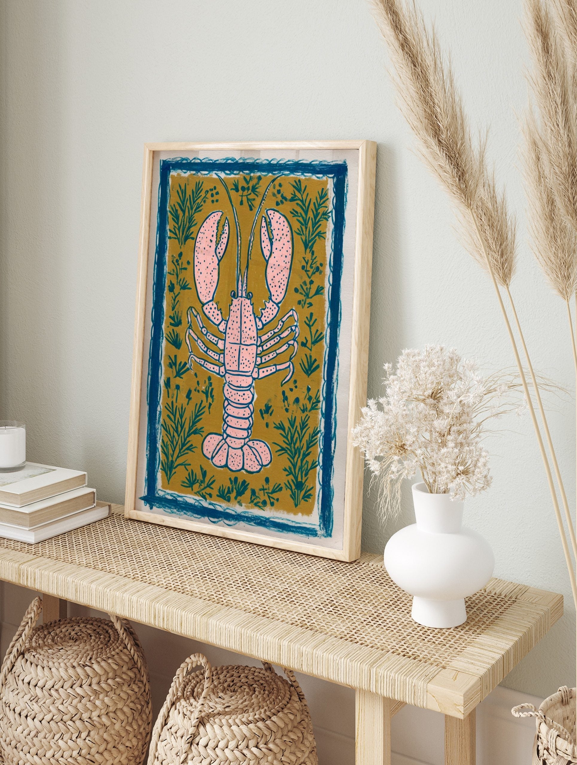 Pink lobster illustration art print on mustard yellow background with teal plants and blue, in an alternate framed mockup