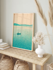 Minimalist teal landscape print with a lone boatman on a lake and distant mountains under a, in an alternate framed mockup