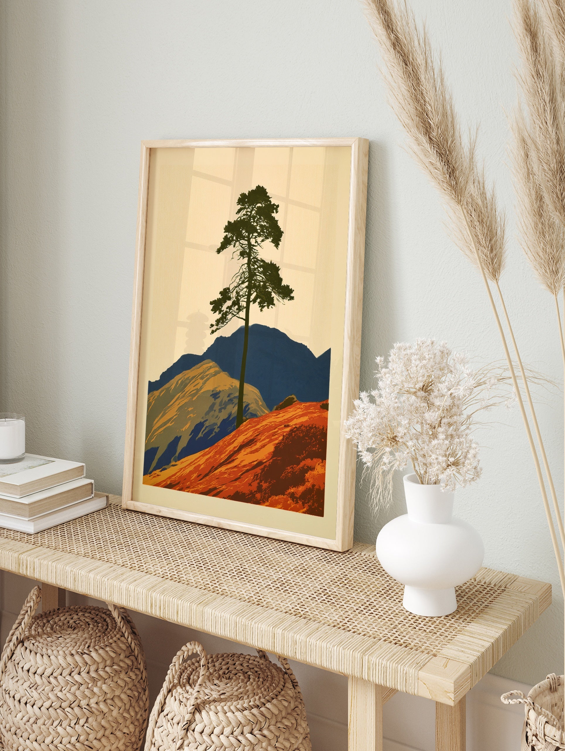 Graphic illustration of a lone pine tree on an orange hill with blue mountains, minimalist, in an alternate framed mockup