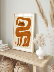 Minimalist wall art print featuring an elongated orange cat illustration with black facial, in an alternate framed mockup