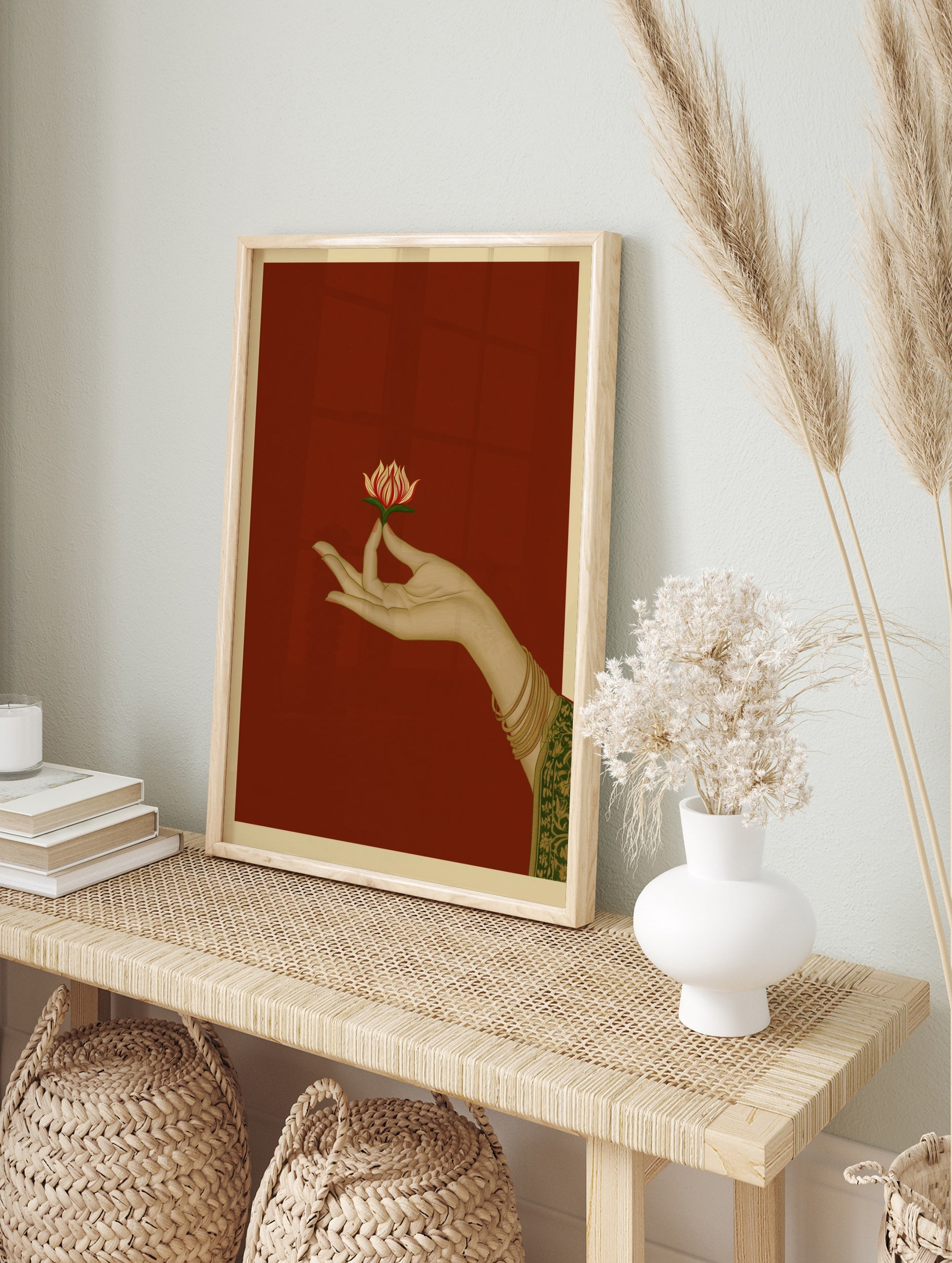 Illustration of a hand holding a lotus flower on a red background, traditional Indian art, in an alternate framed mockup