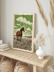 Woodcut style print of a brown horse with a white blaze standing in tall grass under a green, in an alternate framed mockup