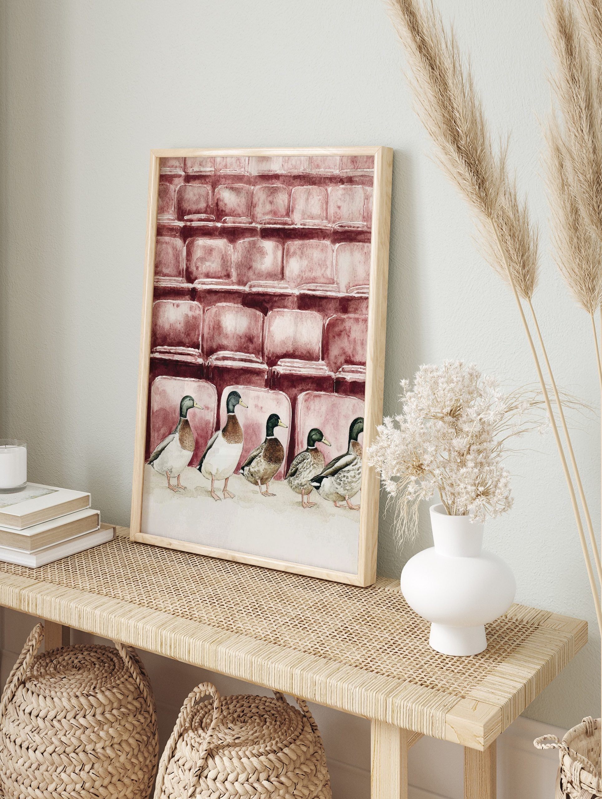 Watercolour illustration of five mallard ducks in a row in front of reddish-brown theatre, in an alternate framed mockup
