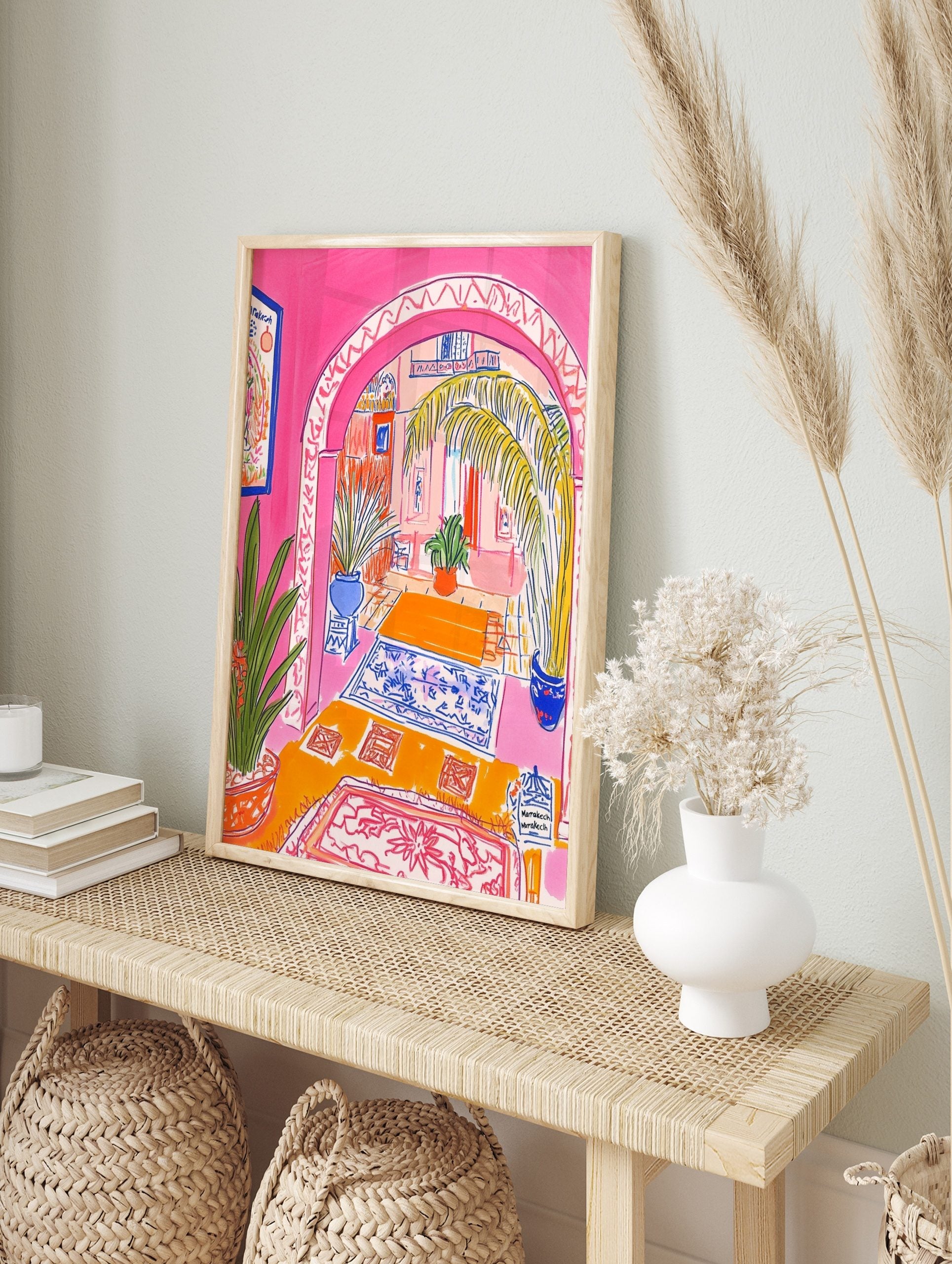 Vibrant illustrative print of a Moroccan archway interior with pink walls, palm tree, and, in an alternate framed mockup
