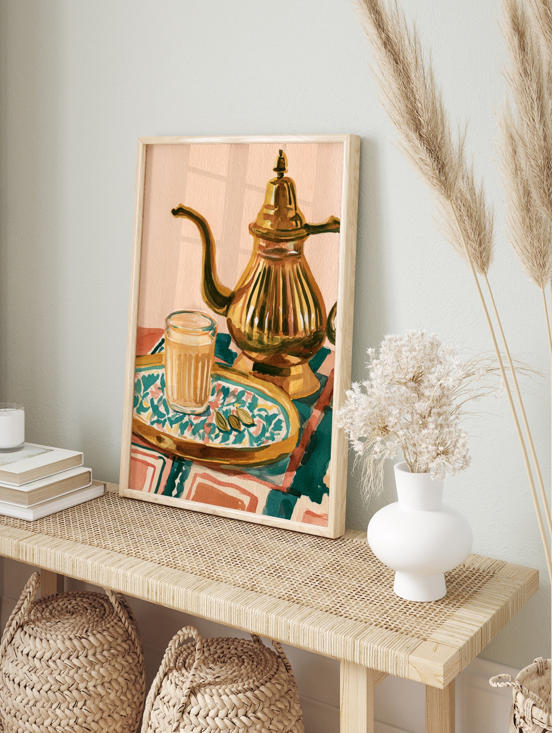 Illustrative art print of a glass of masala chai, a metallic teapot, and cardamom pods on a, in an alternate framed mockup