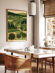 Illustrative rural landscape print with green agricultural fields, cypress trees, and orange fruit, in a styled room mockup