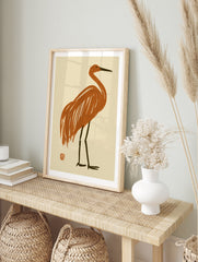 Minimalist crane bird illustration in burnt orange with dark legs on a cream background, in an alternate framed mockup