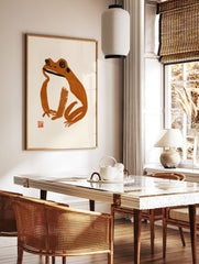 Minimalist frog illustration in brown brush strokes with a red seal on a cream background art print, in a styled room mockup