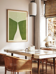 Minimalist abstract art print with rolling green hills, a white path, and a pale circle on a light, in a styled room mockup