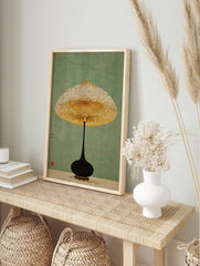 Minimalist lamp wall art with a golden textured shade and black base on a green background, in an alternate framed mockup