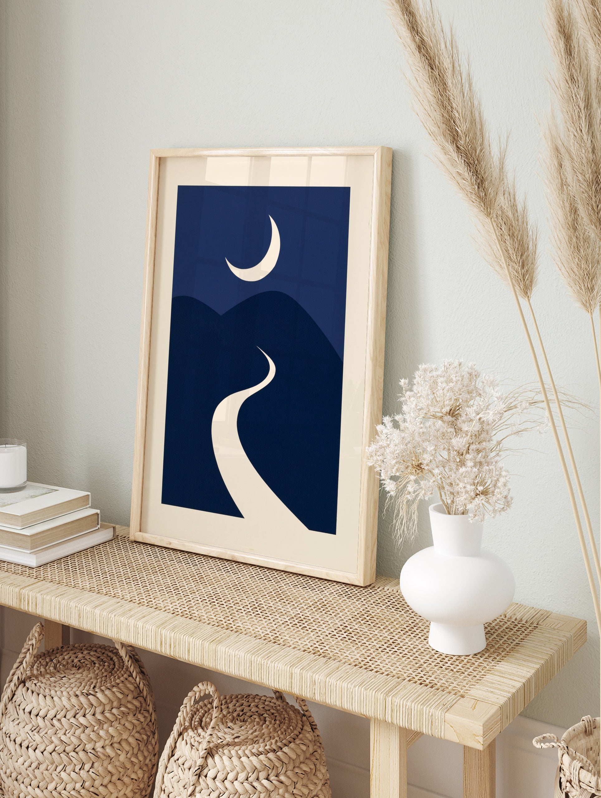 Minimalist night landscape art print with a cream crescent moon over navy blue rolling hills, in an alternate framed mockup