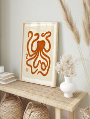 Minimalist octopus illustration with orange brush strokes on a cream background, abstract, in an alternate framed mockup