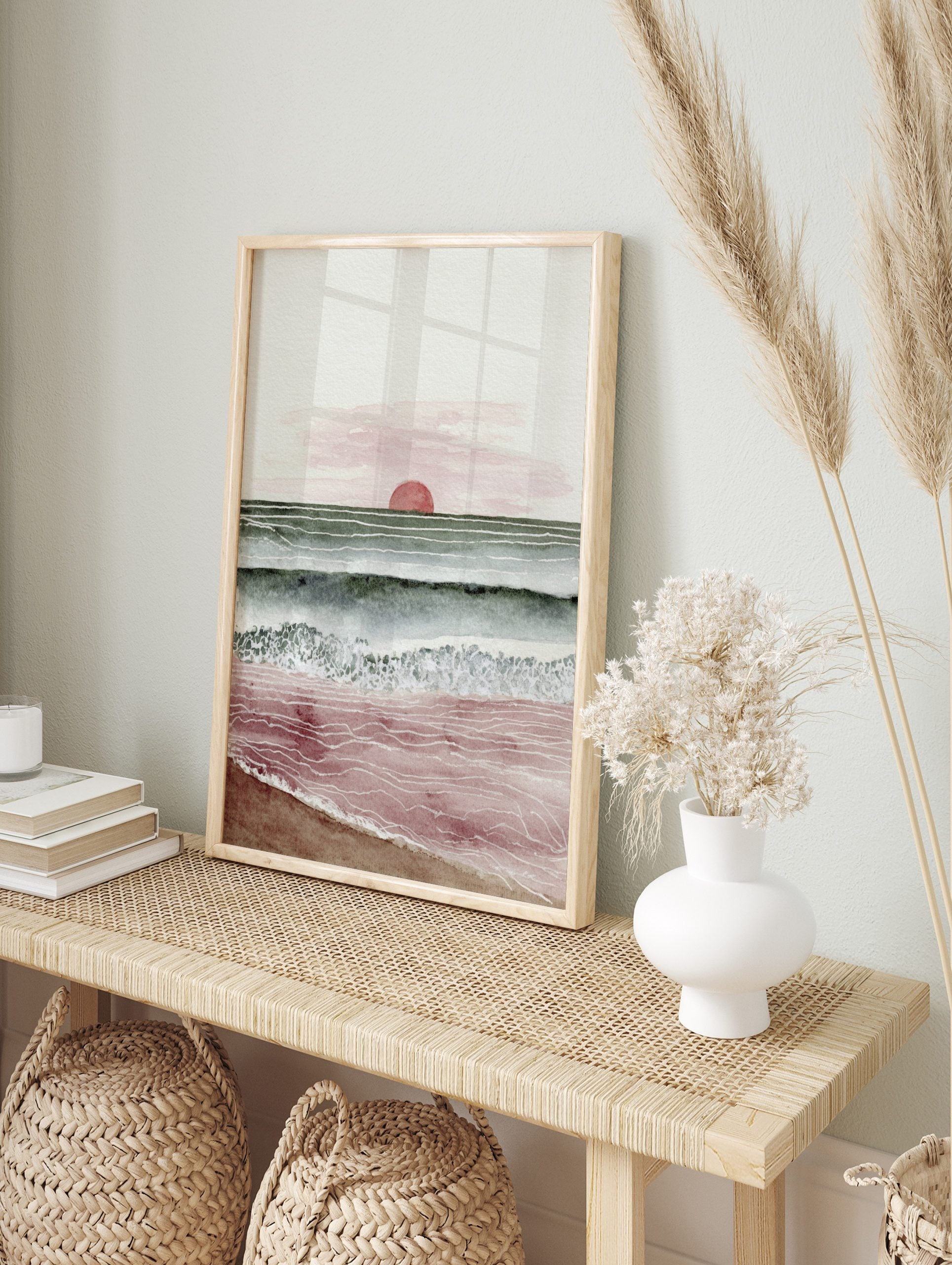 Minimalist watercolour art print of a sunset over the ocean with red sun, green-blue waves, in an alternate framed mockup