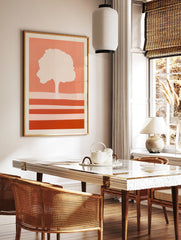 Minimalist tree silhouette art print with horizontal stripes in warm coral and peach tones on a, in a styled room mockup
