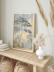 Illustrative misty blue forest landscape art print with tall trees, blue foliage, beige sky, in an alternate framed mockup