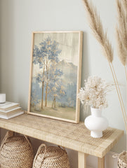 Painterly landscape art print with blue and beige trees, misty forest, and distant mountains, in an alternate framed mockup