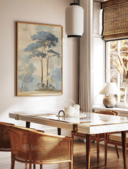 Illustrative misty forest landscape art print with tall blue-leafed trees and white-blossomed bushes, in a styled room mockup
