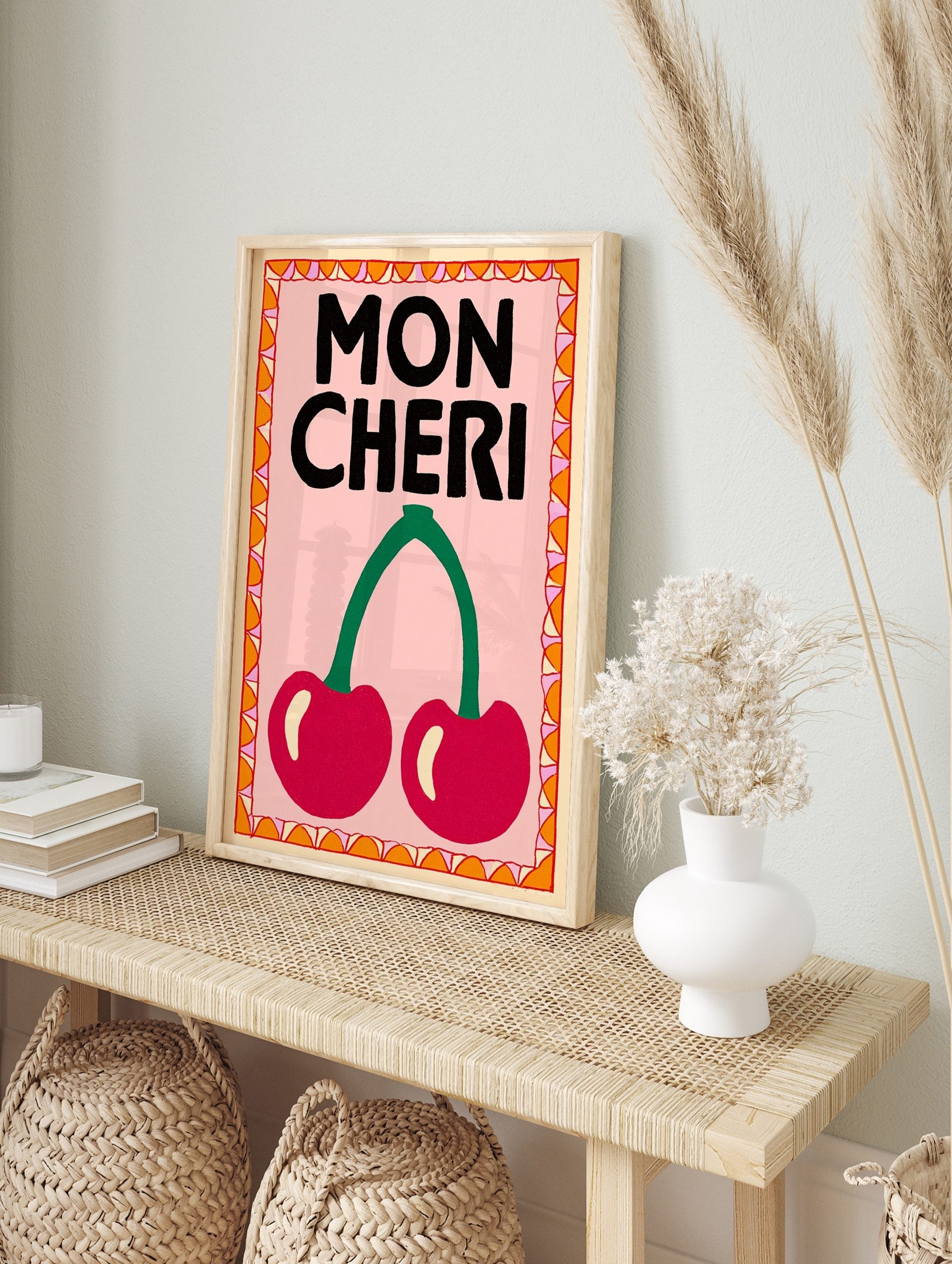 Mon Cheri typography wall art with two red cherries, green stem, pink background, and, in an alternate framed mockup