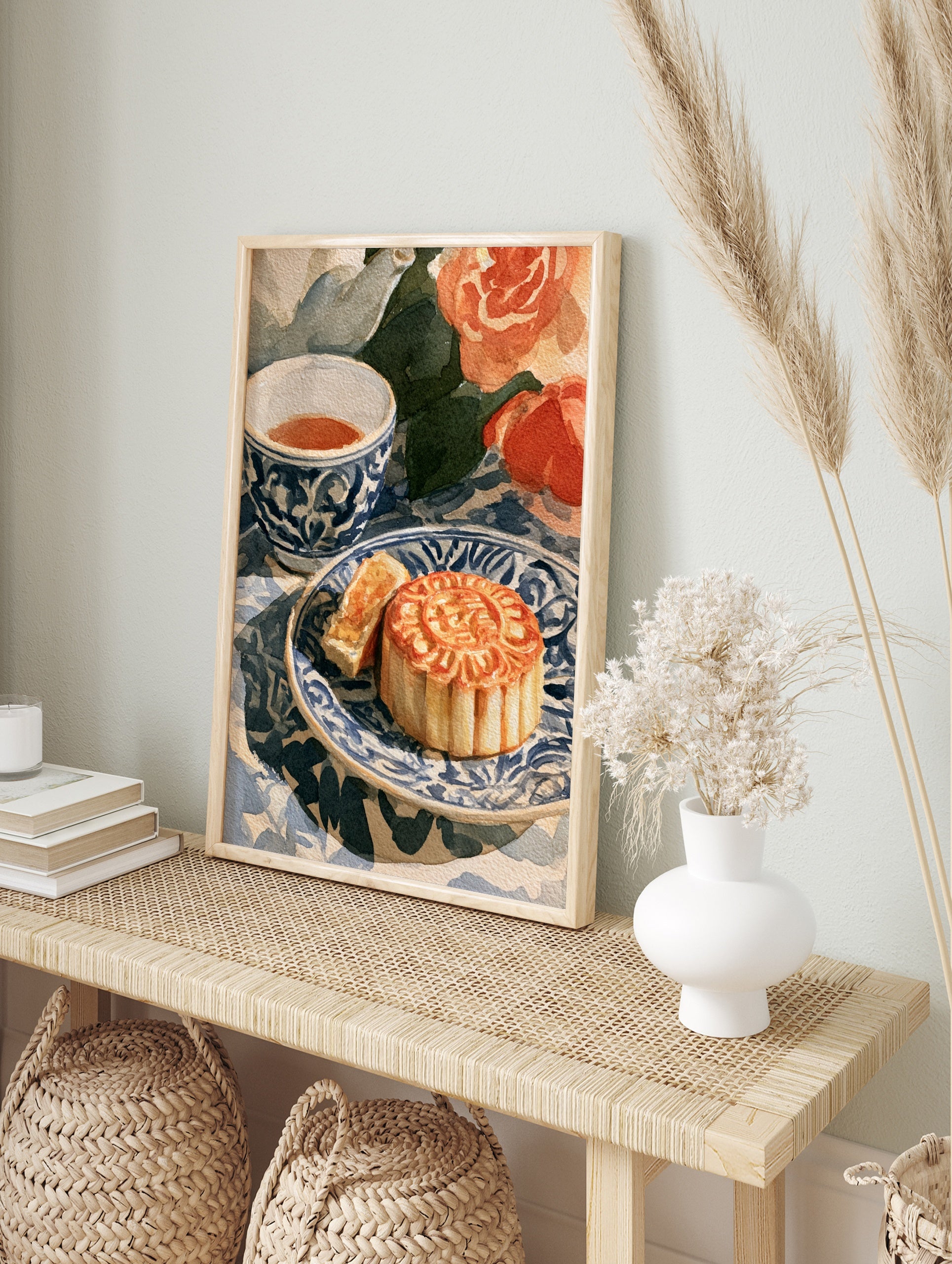Watercolour illustration of a sliced mooncake on a blue and white patterned plate with a, in an alternate framed mockup