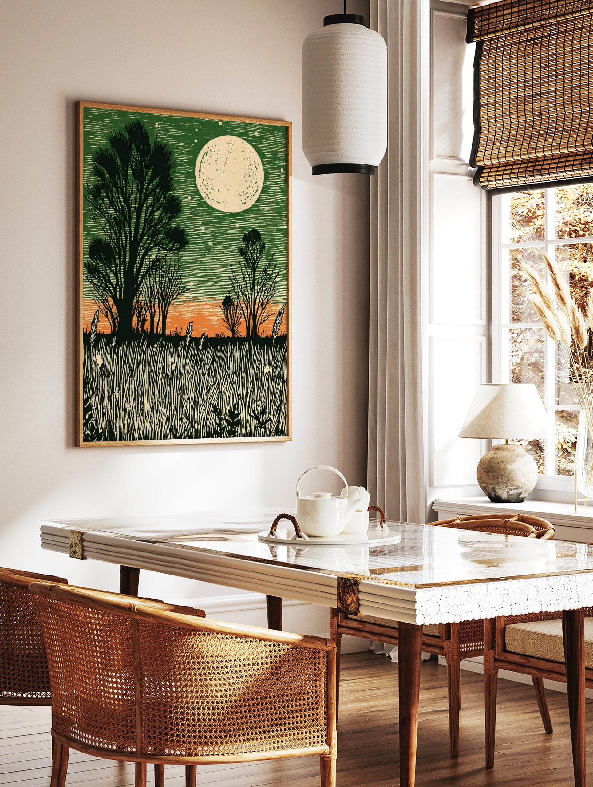 Linocut style moonlit field print with dark green sky, orange horizon, silhouetted trees, and tall, in a styled room mockup