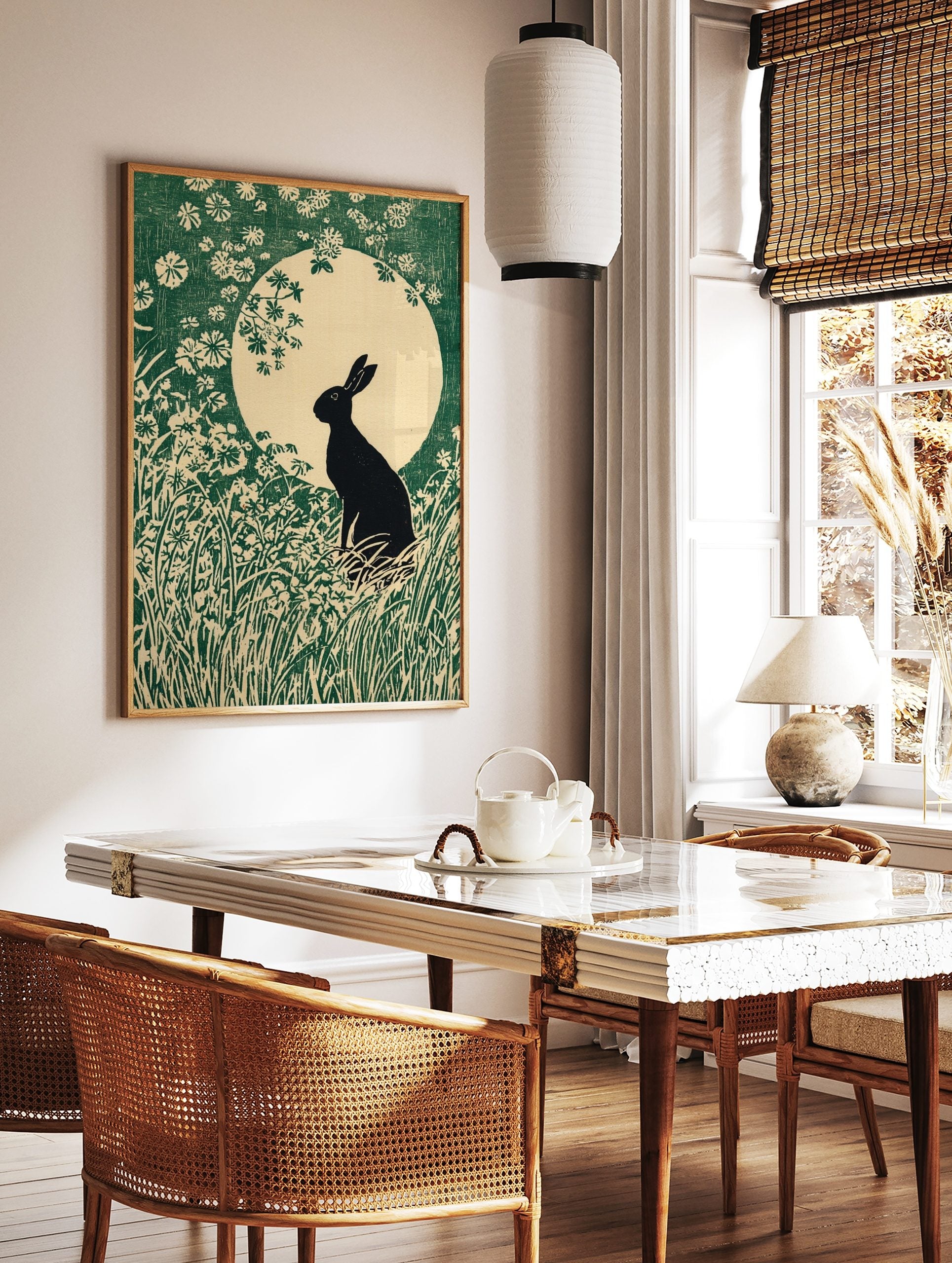 Black rabbit silhouette in a field of green grass and white flowers against a large pale moon in an, in a styled room mockup