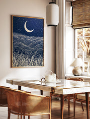 Crescent moon and starry night sky over rolling grass hills in a graphic, navy and cream, in a styled room mockup