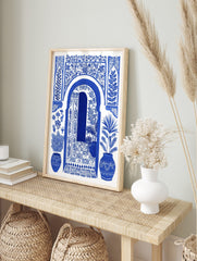 Blue and white illustrative art print of a Moroccan arched doorway with open door, botanical, in an alternate framed mockup
