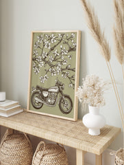 Vintage motorcycle parked under blooming cherry blossom tree in illustrative green, white, in an alternate framed mockup